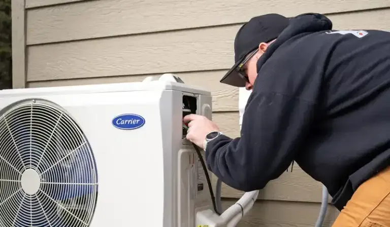 Licensed HVAC technician installing a new air conditioning unit to replace an old system.