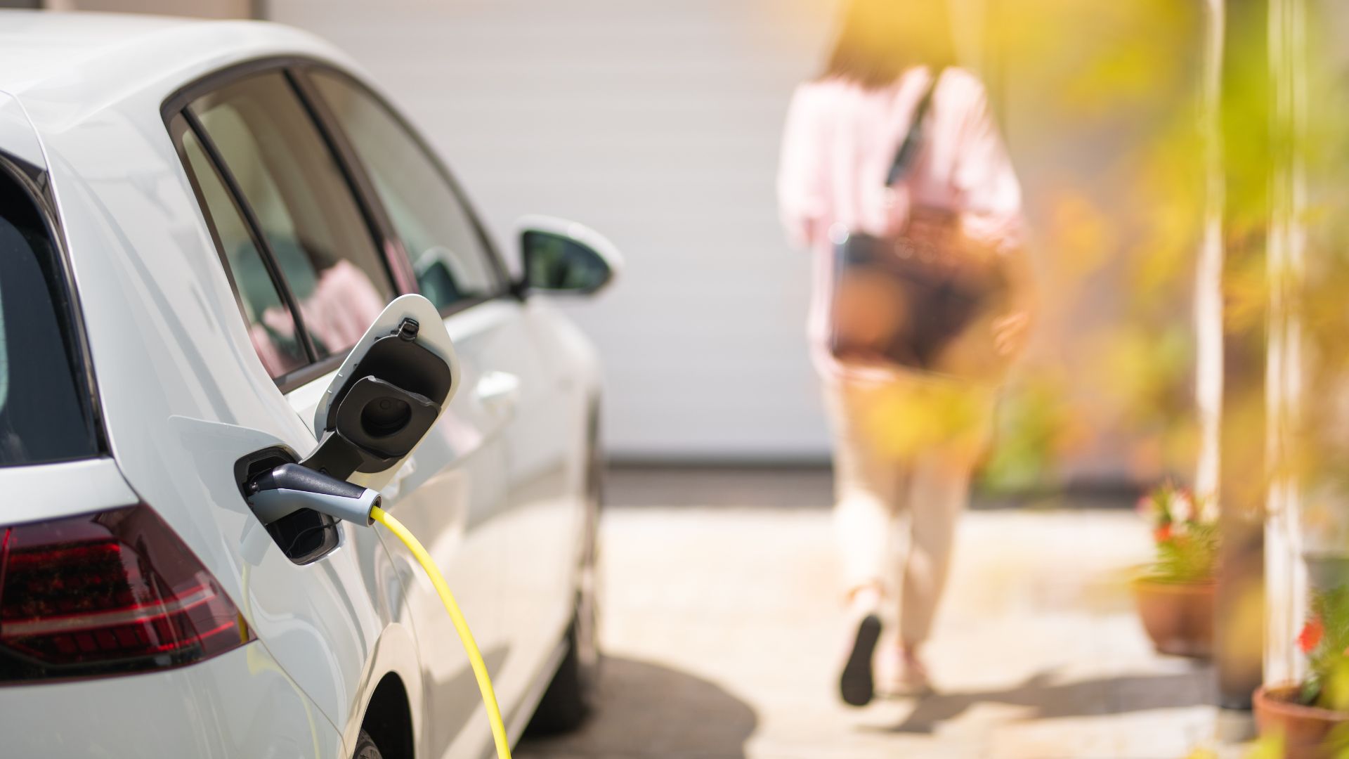 Image of a electric vehicle charging station with a woman walking away from the car