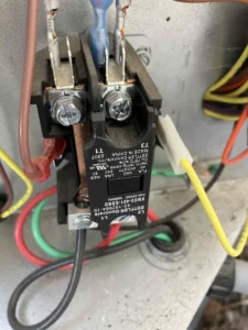 Technician inspecting failed part inside outdoor AC unit during AC repair in Bend, OR.