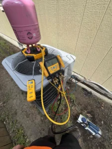Bend air conditioner repair technician adjusting refrigerant charge to restore cooling system performance