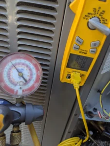 Technician testing electrical components on newly installed AC system during repair in Bend home.